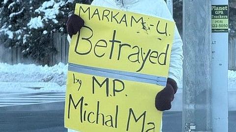 A protestor holding a sign saying that MP Michael Ma betrayed his constituents