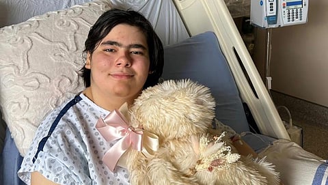 A photo of Paige Hoekstra, one of the injured victims from the Tumbler Ridge school shooting, sitting in a hospital bed. 