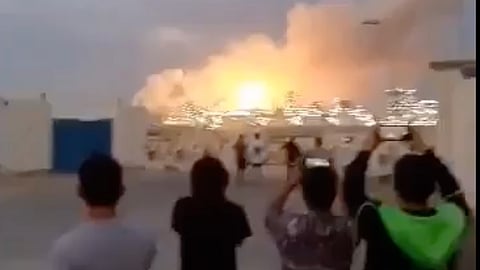 Onlookers take pictures and videos of a fire at the Bahrain Petroleum Company in Ma'ameer after an Iranian missile strike