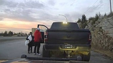 A man and his son take belongings out of a Dodge pickup that is being towed to an impound lot